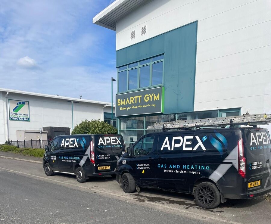 Two Apex Gas and Heating branded vans parked outside a client site